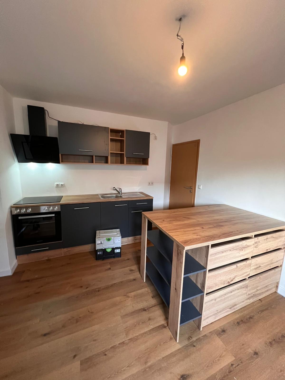 Montage einer anthrazitfarbenen Küche mit großer Kücheninsel aus Holz